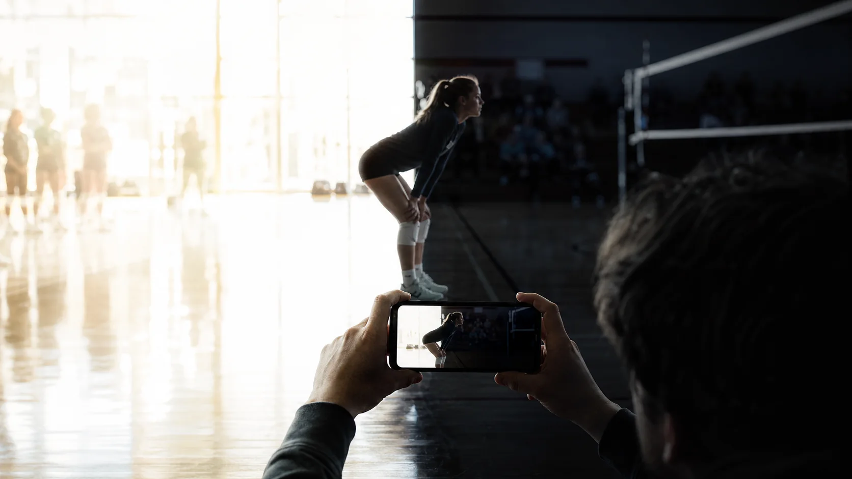 QShot exposure pain point: a volleyball player divided between blown highlights and deep gym shadows